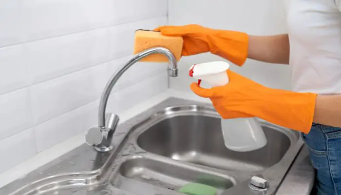 Putting soapy solution to clean nickel faucet